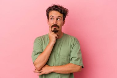 Pembe arka planda izole edilmiş genç beyaz adam bir strateji planlıyor, bir iş yolu düşünüyor..