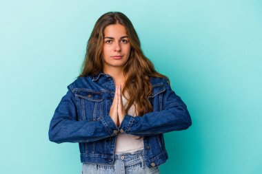 Kafkasyalı genç kadın mavi arka planda izole edilmiş dua ediyor, bağlılık gösteriyor, dindar biri ilahi ilham arıyor..