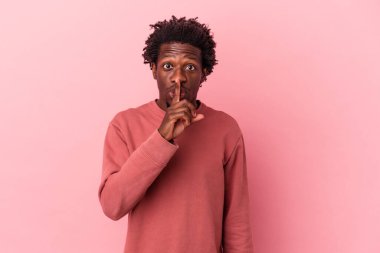 Genç Afrikalı Amerikalı bir adam pembe arka planda izole edilmiş bir şekilde sır saklıyor ya da sessizlik istiyor..