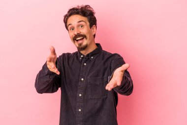 Pembe arka planda izole edilmiş genç beyaz adam kameraya sarıldığı için kendinden emin hissediyor..