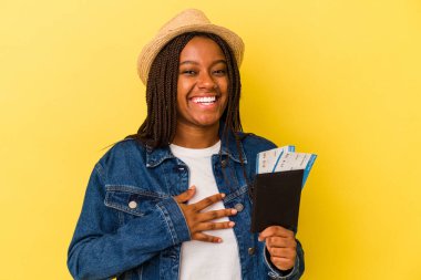 Sarı arka planda pasaportu olan Afrikalı Amerikalı genç bir kadın elini göğsüne koyduğunda kahkahalar atıyor..