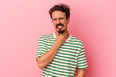 Kafkasyalı genç bir adam pembe arka planda izole edilmiş kafasının arkasına dokunuyor, düşünüyor ve bir seçim yapıyor..