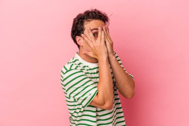 Pembe arka planda izole edilmiş genç beyaz adam parmaklarıyla gözünü kırp korkmuş ve gergin..