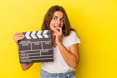 Elinde klaket tutan beyaz bir kadın sarı arka planda izole edilmiş. Bir şeyin fotokopi odasına baktığını düşünüyor..