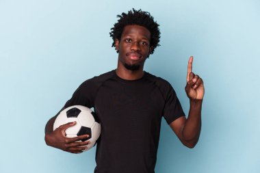 Amerikan futbolu oynayan genç Afrikalı bir adam mavi arka planda bir numarayı parmağıyla gösteriyor..