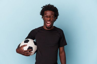 Amerikan futbolu oynayan genç Afro-Amerikan bir adam mavi arka planda izole edilmiş çok kızgın ve agresif çığlıklar atıyor..