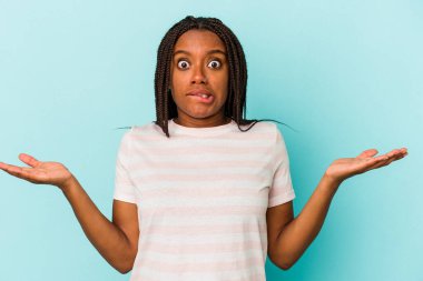 Genç Afrikalı Amerikalı kadın, mavi arka planda izole edilmiş. Kafası karışmış ve omuz silkiyor. Kopya alanını tutmak için..