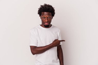 Beyaz arka planda izole edilmiş genç Afrikalı Amerikalı adam gülümsüyor ve boş alanda bir şeyler gösteriyor..