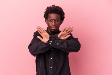 Pembe arka planda izole edilmiş genç Afro-Amerikan adam inkar jesti yapıyor.