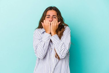 Mavi arka planda izole edilmiş, tırnak yiyen, gergin ve endişeli bir beyaz kadın..