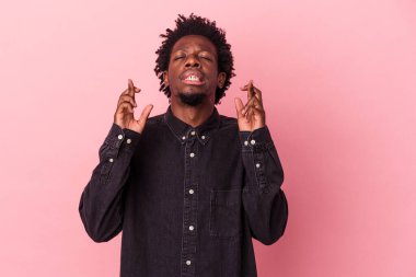 Genç Afrikalı Amerikalı adam pembe arka planda izole edilmiş şans diliyor.