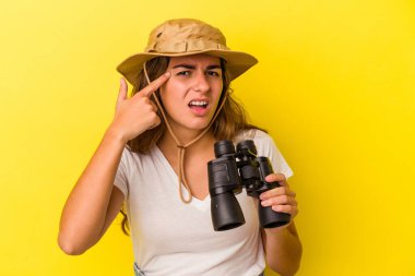 Sarı arka planda dürbün tutan beyaz bir kadın işaret parmağıyla hayal kırıklığına uğradığını gösteriyor..