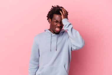 Genç Afrikalı Amerikalı bir adam pembe arka planda izole edilmiş bir şekilde bir şeyi unutuyor. Alnına avuç içi ve kapalı gözlerle tokat atıyor..