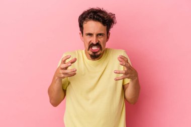 Pembe arka planda izole edilmiş genç beyaz adam gergin elleriyle çığlık atıyor..