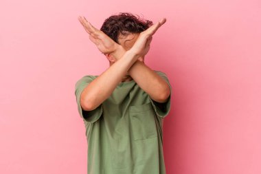 Pembe arka planda izole genç beyaz adam iki kolu çapraz tutuyor, inkar kavramı.