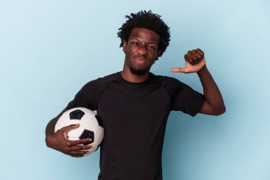 Mavi arka planda futbol oynayan genç Afrikalı Amerikalı adam gururlu ve kendinden emin, örnek olarak....