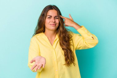 Beyaz bir kadın mavi arka planda izole edilmiş ve elinde bir ürün tutuyor..