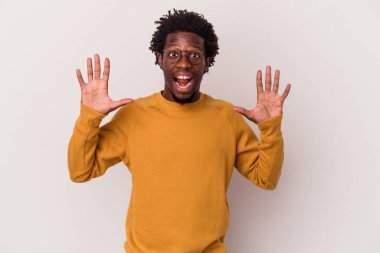 Beyaz arka planda izole edilmiş genç Afrikalı Amerikalı hoş bir sürpriz alıyor, heyecanlı ve el kaldırıyor..