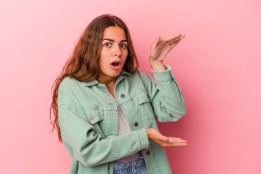 Pembe arka planda izole edilmiş genç beyaz kadın elleri arasında bir kopya alanı tutarken şok ve hayrete düştü..