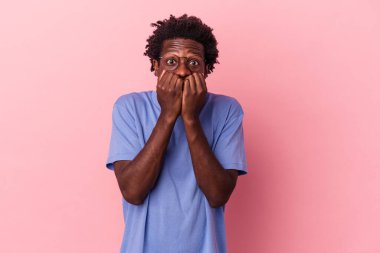 Genç Afrikalı Amerikalı bir adam pembe arka planda izole edilmiş tırnak yiyor, gergin ve çok endişeli..