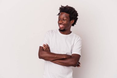 Beyaz arka planda izole edilmiş genç Afro-Amerikalı adam kollarını kavuşturarak gülümsüyor..