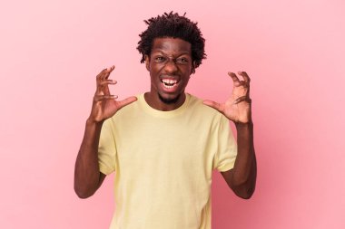 Genç Afrikalı Amerikalı adam pembe arka planda izole edilmiş öfkeyle bağırıyor..