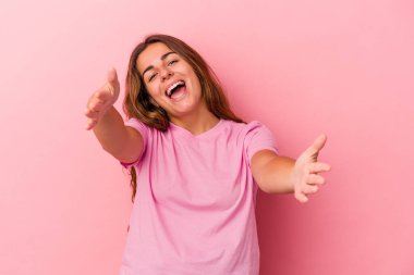 Pembe arka planda izole edilmiş genç beyaz kadın kameraya sarıldığı için kendinden emin..