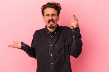 Pembe arka planda izole edilmiş genç beyaz adam elinde bir ürün tutuyor..