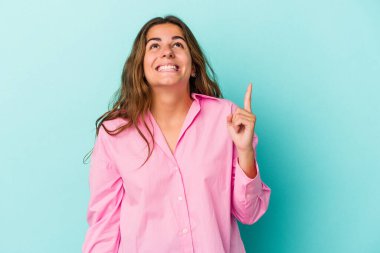 Mavi arka planda izole edilmiş genç beyaz kadın iki parmağı da boş bir alan gösteriyor..