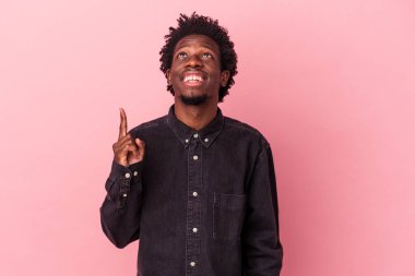 Pembe arka planda izole edilmiş genç Afrikalı Amerikalı iki parmağı da boş bir alan gösteriyor..