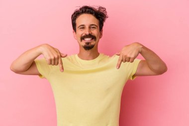 Pembe arka planda izole edilmiş genç beyaz adam parmaklarıyla aşağıya doğru, olumlu bir his..