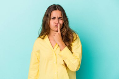 Kafkasyalı genç kadın mavi arka planda izole edilmiş düşünüyor ve yukarı bakıyor, yansıtıyor, düşünüyor, bir fantezi kuruyor..