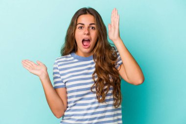 Mavi arka planda izole edilmiş beyaz bir kadın avuç içinde fotokopi alanı tutuyor, el üstünde tutuyor. Şaşırmış ve mutlu..