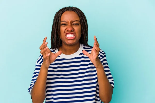 Genç Afrikalı Amerikalı kadın mavi arka planda izole edilmiş gergin ellerle çığlık atıyor..