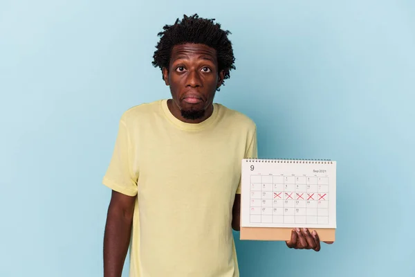 Mladý Africký Američan Drží Kalendář Izolované Modrém Pozadí Pokrčí Rameny — Stock fotografie