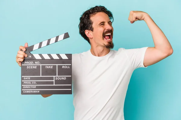 Young Caucasian Man Holding Clapperboard Isolated Blue Background Raising Fist — Stock Photo, Image