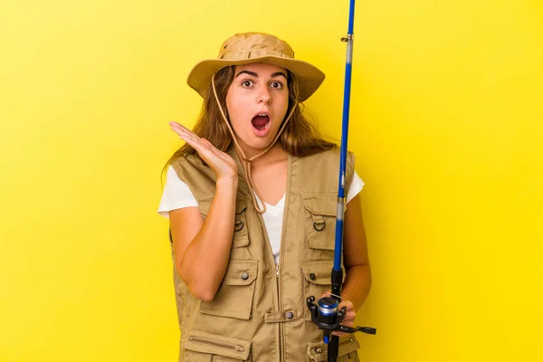 Young Caucasian Fisherwoman Holding Rod Isolated Yellow Background Surprised Shocked — Stock Photo, Image