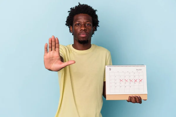 Jonge Afro Amerikaanse Man Houdt Kalender Geïsoleerd Blauwe Achtergrond Staan — Stockfoto