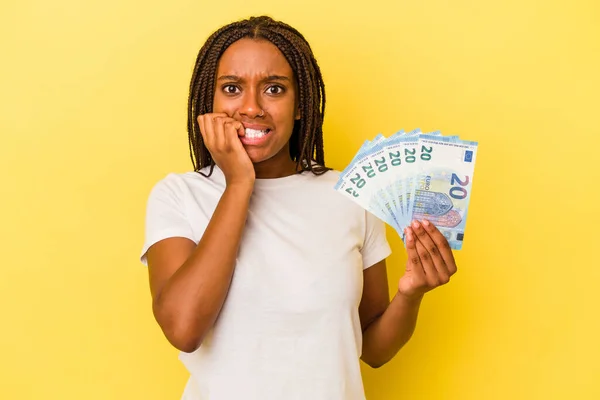 Молодая Африканская Американка Держит Банкноты Изолированы Желтом Фоне Грызет Ногти — стоковое фото