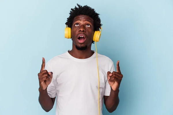 若いですアフリカ系アメリカ人男性に耳を傾け音楽に隔離された上で青の背景を指します逆さまの口 — ストック写真