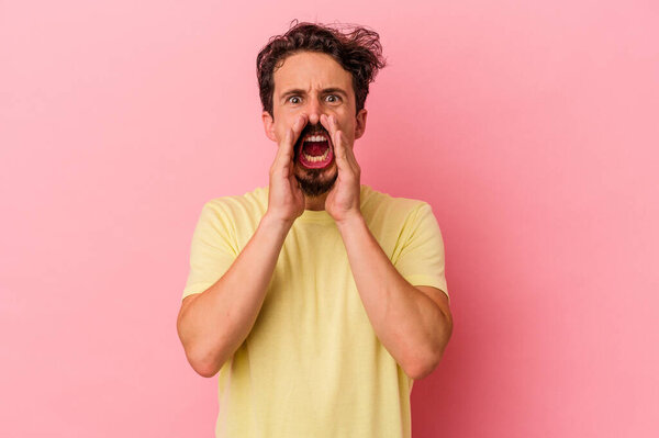 Young caucasian man isolated on pink background shouting excited to front.