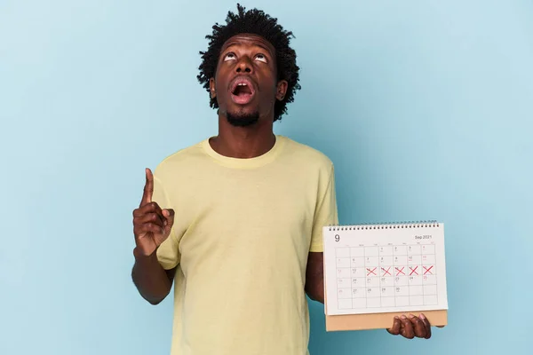 Jong Afrikaans Amerikaanse Man Houden Kalender Geïsoleerd Blauwe Achtergrond Wijzend — Stockfoto