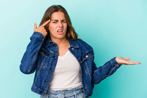 Beyaz bir kadın mavi arka planda izole edilmiş ve elinde bir ürün tutuyor..