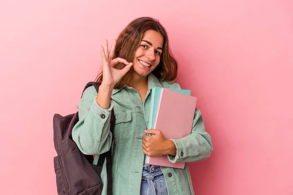 若いですCaucasian学生女性保持本隔離上のピンクの背景陽気で自信を持ってショーOkジェスチャー — ストック写真