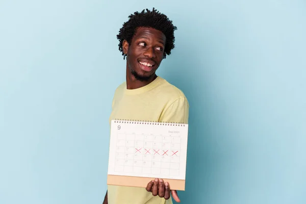 Jonge Afro Amerikaanse Man Houdt Kalender Geïsoleerd Blauwe Achtergrond Kijkt — Stockfoto