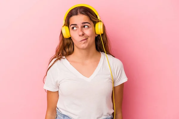 Mulher Caucasiana Jovem Ouvindo Música Isolada Fundo Rosa Confuso Sente — Fotografia de Stock