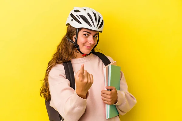 若いですCaucasian学生女性身に着けていますAバイクヘルメット隔離上の黄色背景Pointingとしてあなたに指で近くに来る — ストック写真