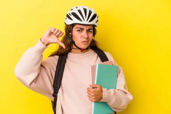 若い白人学生の女性は 黄色の背景には嫌いなジェスチャー 親指を示す隔離された自転車のヘルメットを着ている 意見の相違 — ストック写真