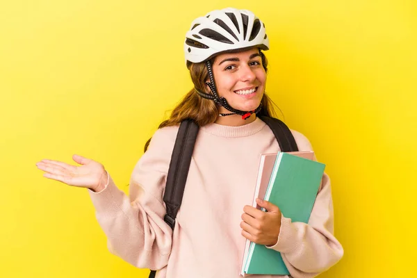 若いです白人学生女性を身に着けています自転車ヘルメット黄色の背景に隔離されたヤシの上にコピースペースを示し 腰に別の手を保持 — ストック写真