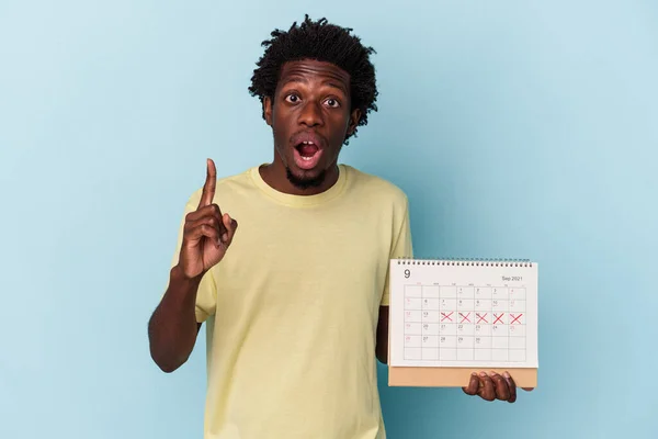 Молодой Африканский Американец Держит Календарь Изолирован Синем Фоне Имея Идею — стоковое фото